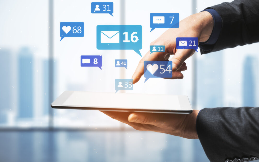 Close up of businessman hand pointing at tablet with social media icons on blurry bright office interior background. Communication, network, connections, device and app concept.